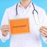 Doctor with text Hemorrhoid and suppositories on blue background